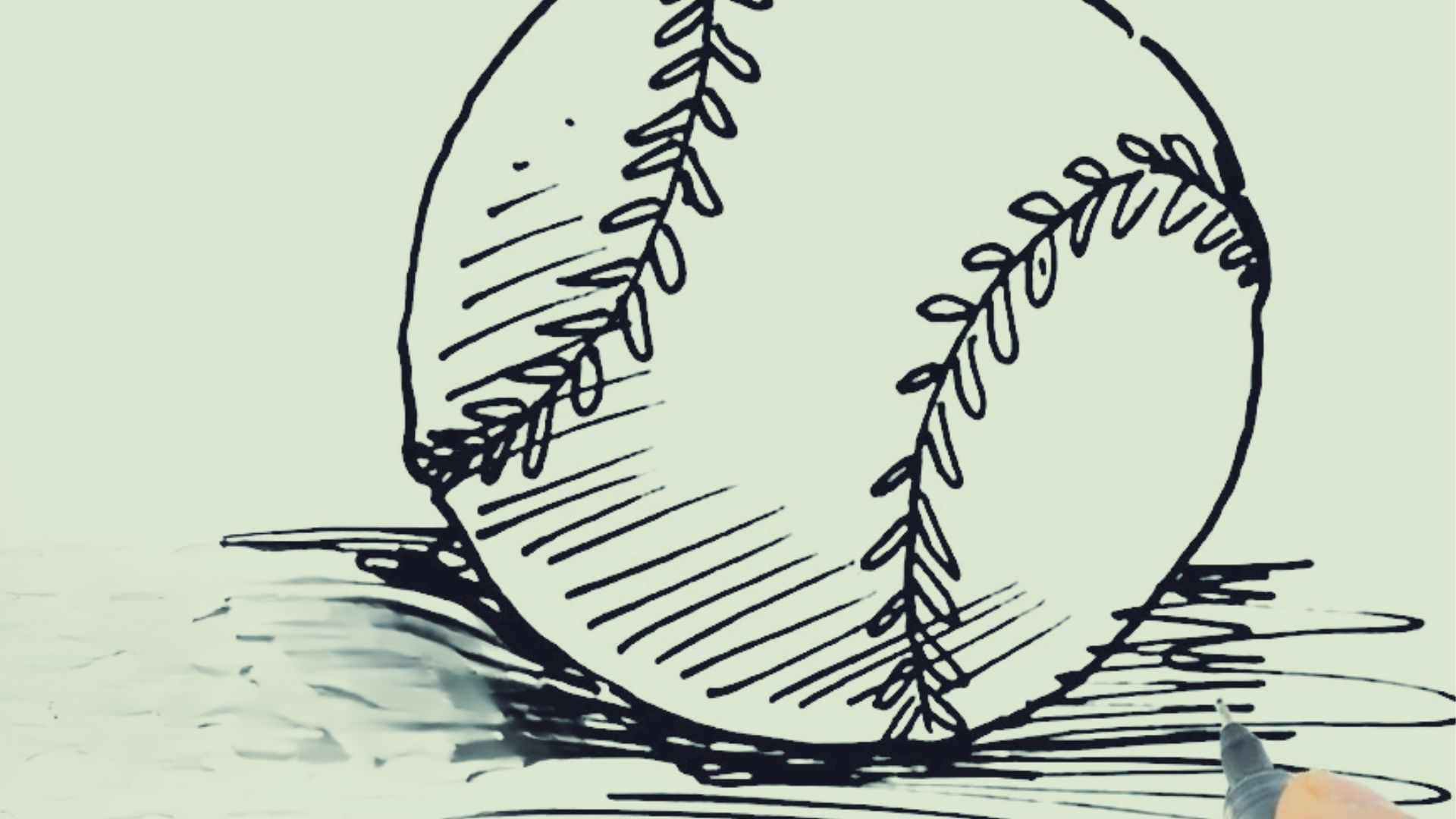 Hand uses black pen to draw baseball sketch with bold stitching on white paper for easy art guide