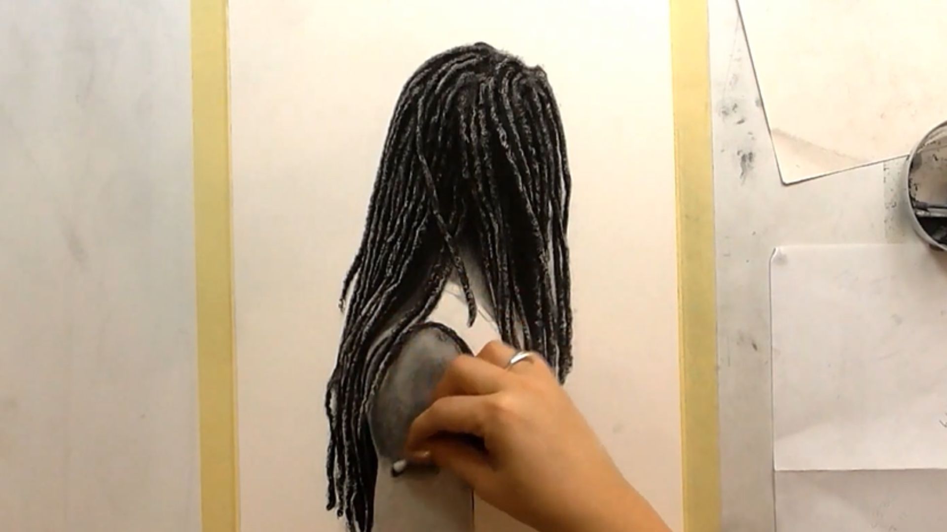 "A person sketches a portrait of a woman with dreadlocks, focusing on her facial features and hairstyle."