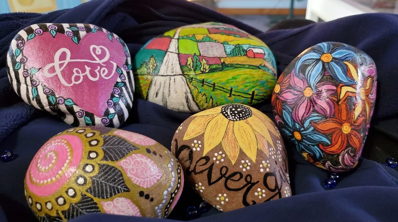 A collection of colorful painted rocks displayed at a rock art gallery, showcasing various artistic designs and patterns