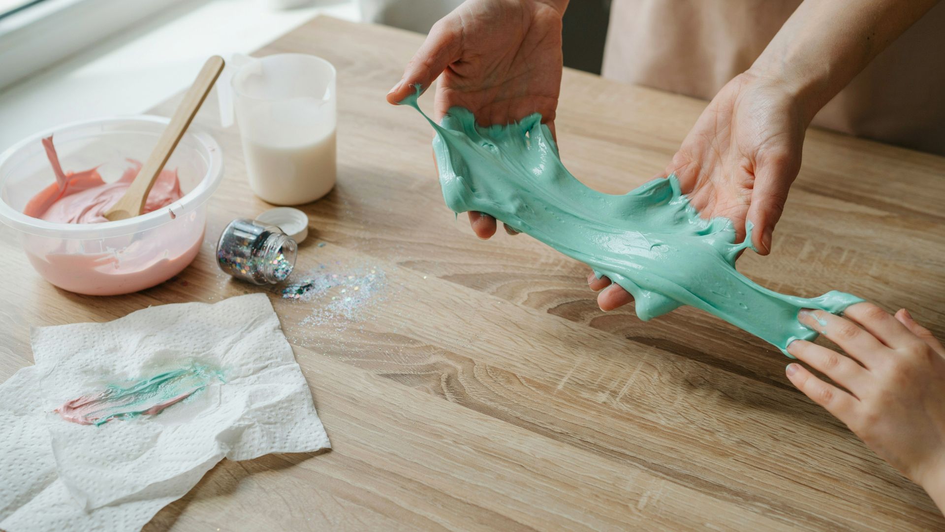 Hands kneading homemade slime until it becomes soft, smooth, and stretchy.