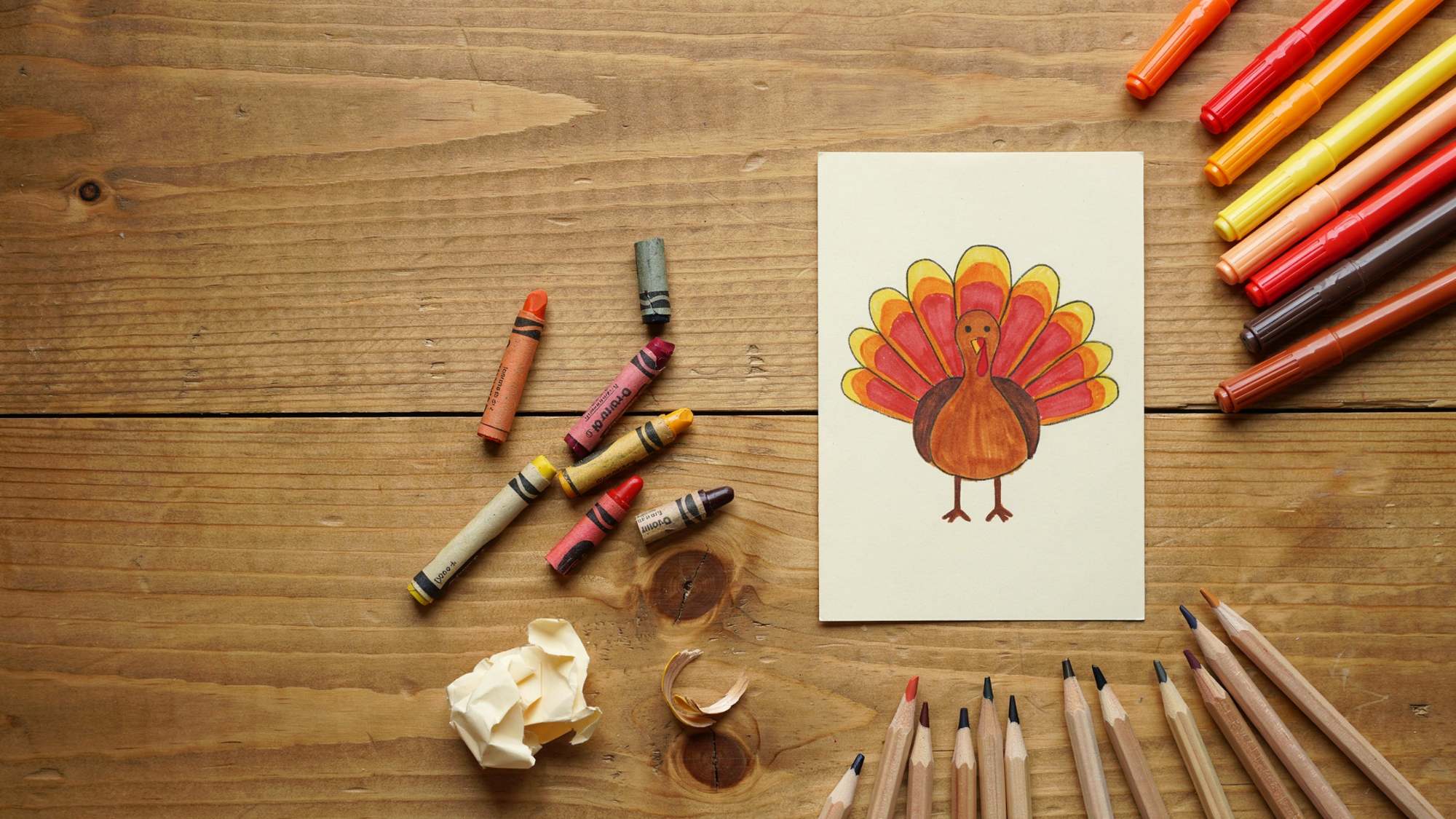 Coloring supplies placed around a colorful turkey drawing