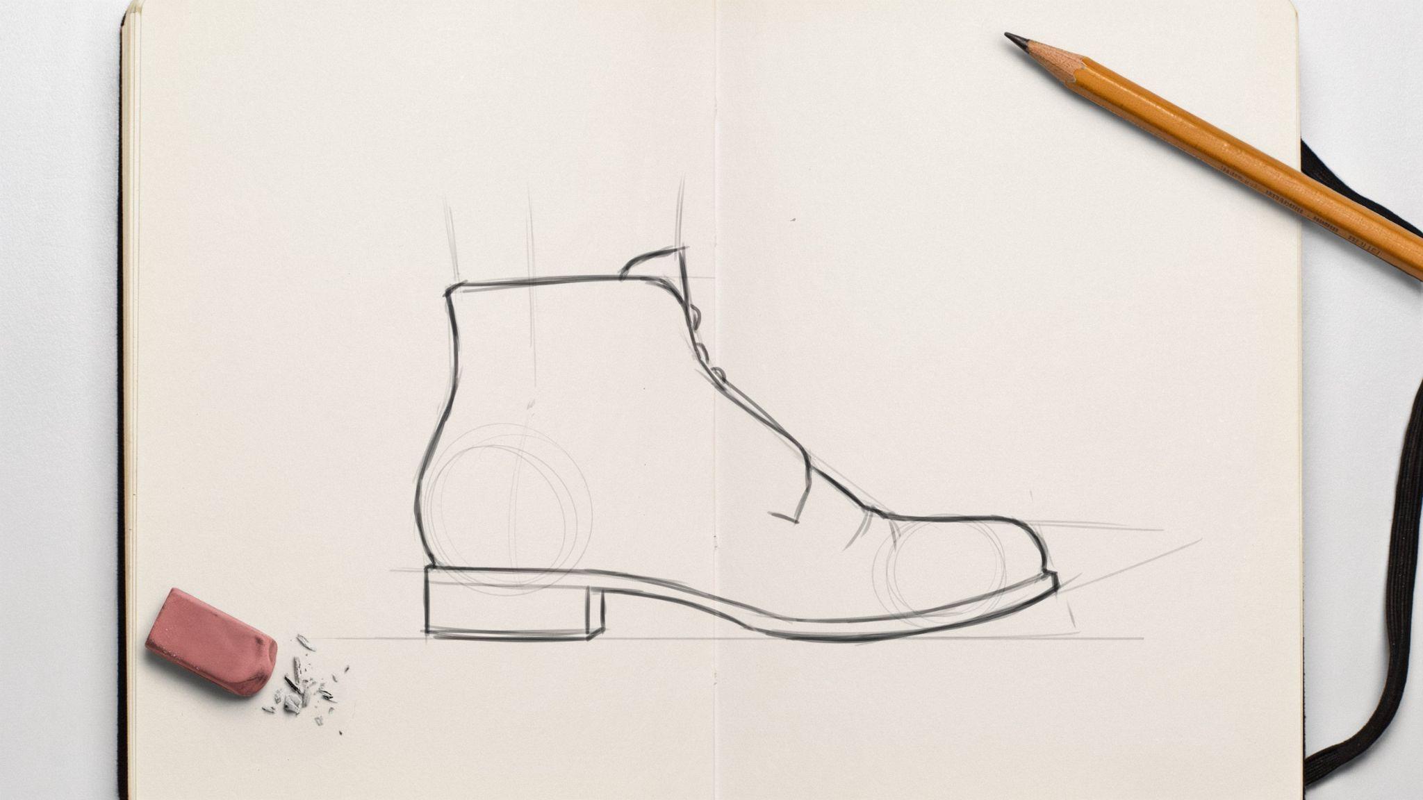 A boot sketch on notebook with pencil, eraser, and eraser shavings around.